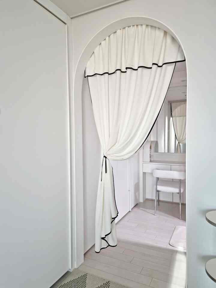 白地に黒縁のカーテンが掛かるウォークインクローゼットの入口、明るく整った印象的な空間