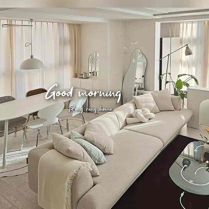 明るいホワイトと木目調が調和するリビング、長いモジュールソファとダイニングテーブル、インテリアミラーや照明が配置された居心地の良い空間