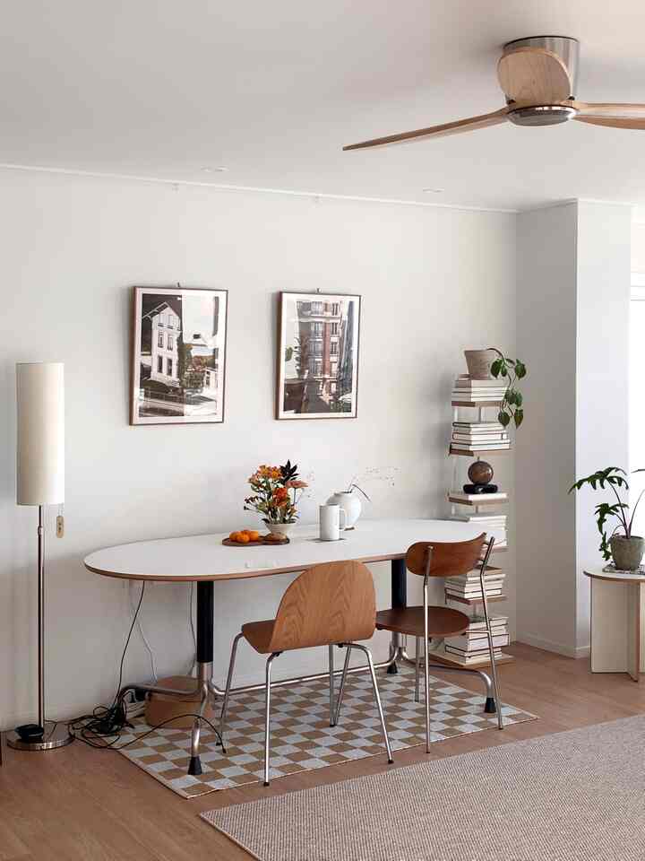 白い壁と木目調家具が調和するナチュラルモダンなダイニングルーム、花瓶と本棚が配されたすっきりとした空間