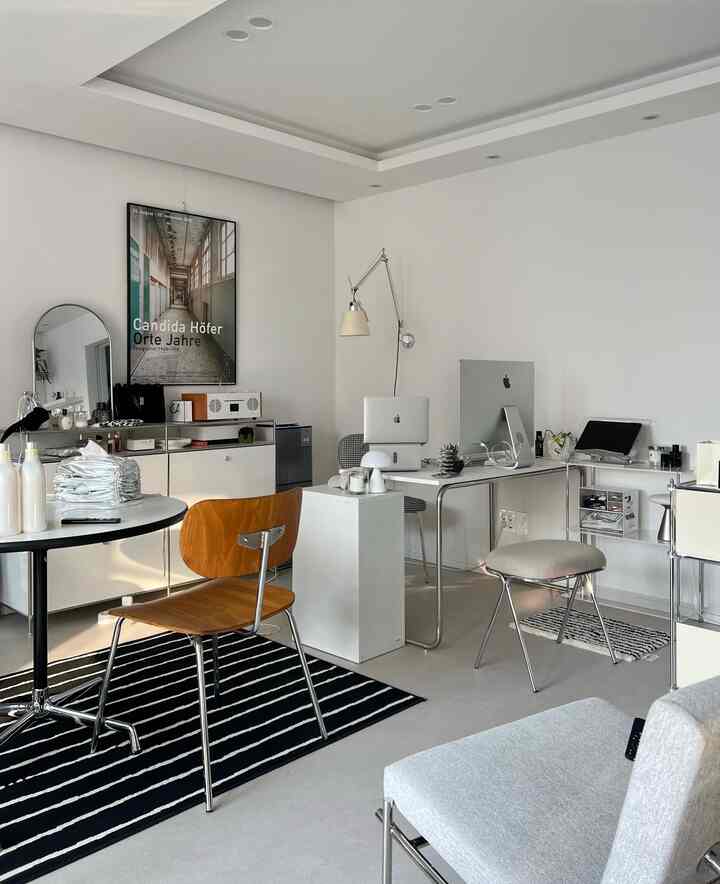 ホワイトトーンのモダンなホームオフィス、アップル製品とミニマルな家具が配置された清潔感のある作業空間