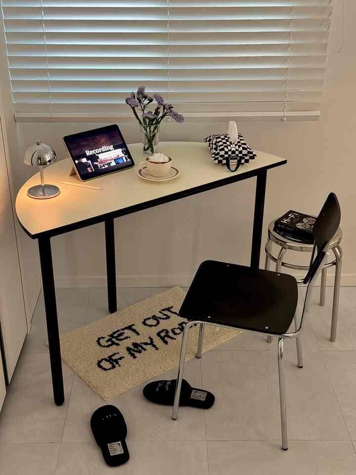 A modern home cafe in a small room featuring a black and white half-round table with a design chair and cozy decor elements