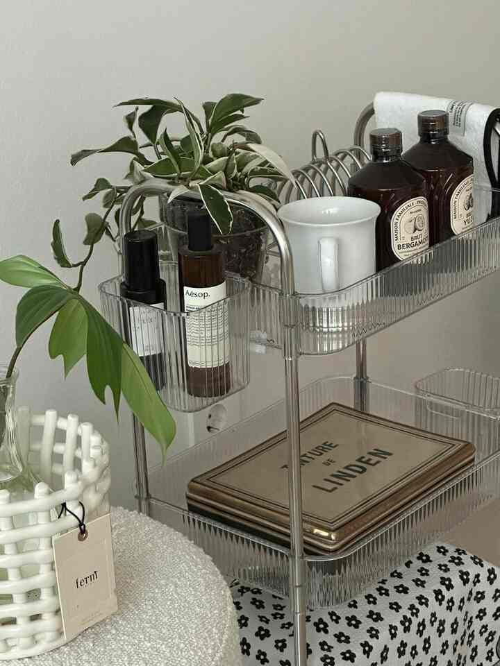 白い背景の透明なアクリル製3段トロリーに植物と飲料用具がきれいに収納された雰囲気のあるインテリア