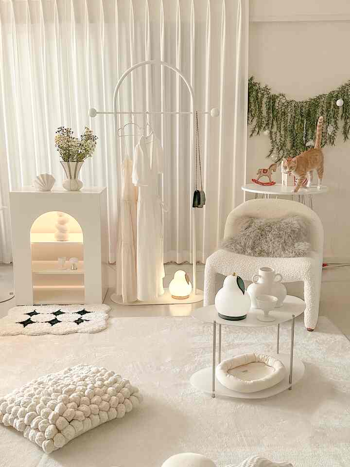 White and ivory toned living room featuring a boucle armchair, rug, vases and decorative objets with a natural and cozy atmosphere