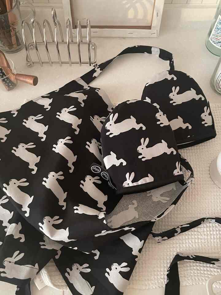 黒と白のウサギ柄のエプロンと手袋がキッチンのカウンターに置かれた、かわいらしいキッチン用品のある雰囲気のインテリア