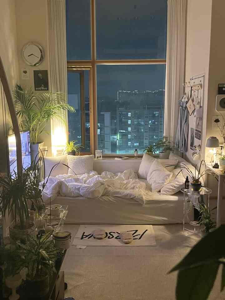 白を基調とした寝室、広い窓と多様な植物が配置された印象的でモダンなインテリア