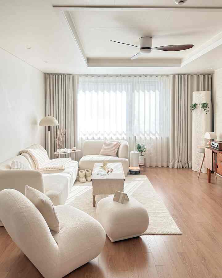 ナチュラルカラーの明るいリビング、アイボリーのソファと木目調の床が温かみのある雰囲気を演出