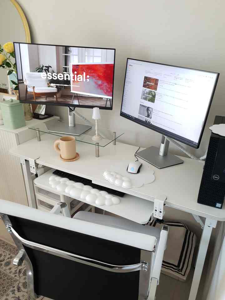 白とシルバーのトーンのホームオフィス、デュアルモニターとモニタースタンドが配置された整然とした作業空間