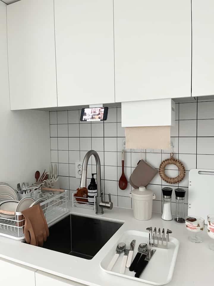 白を基調としたキッチン、シンクと整頓された調理器具が配置されたモダンで清潔なインテリア