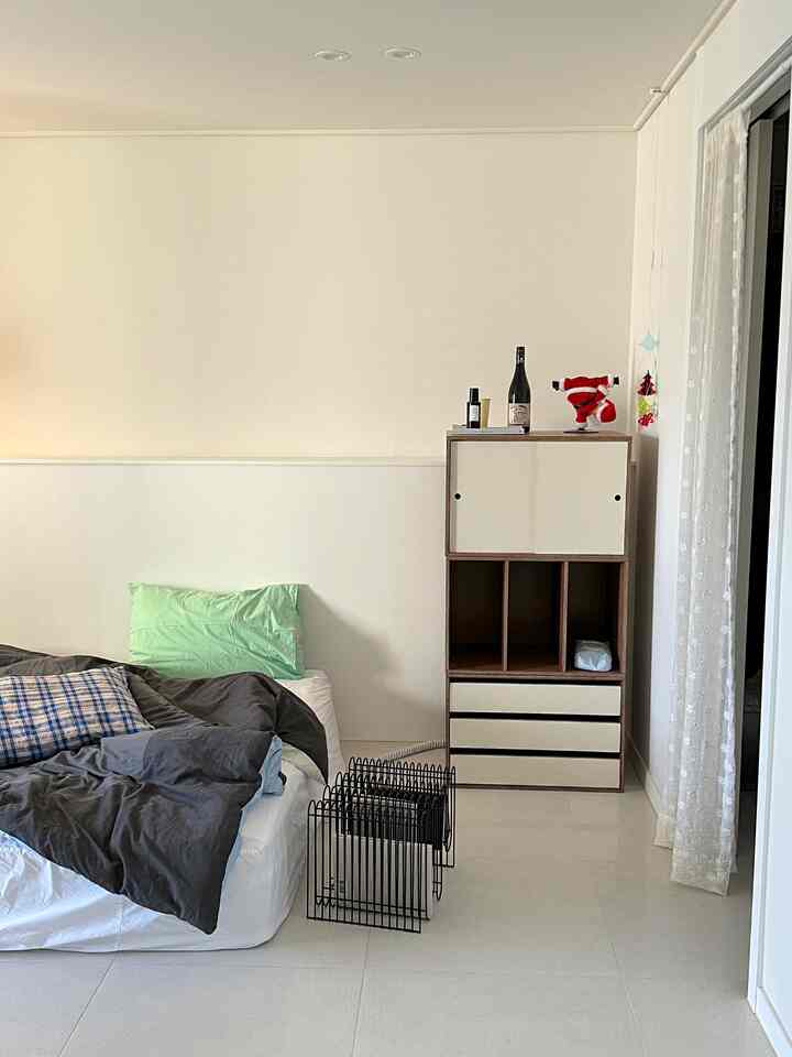 ナチュラルな色調の寝室、マットレスとチェック柄の枕が置かれたシンプルで落ち着いた空間