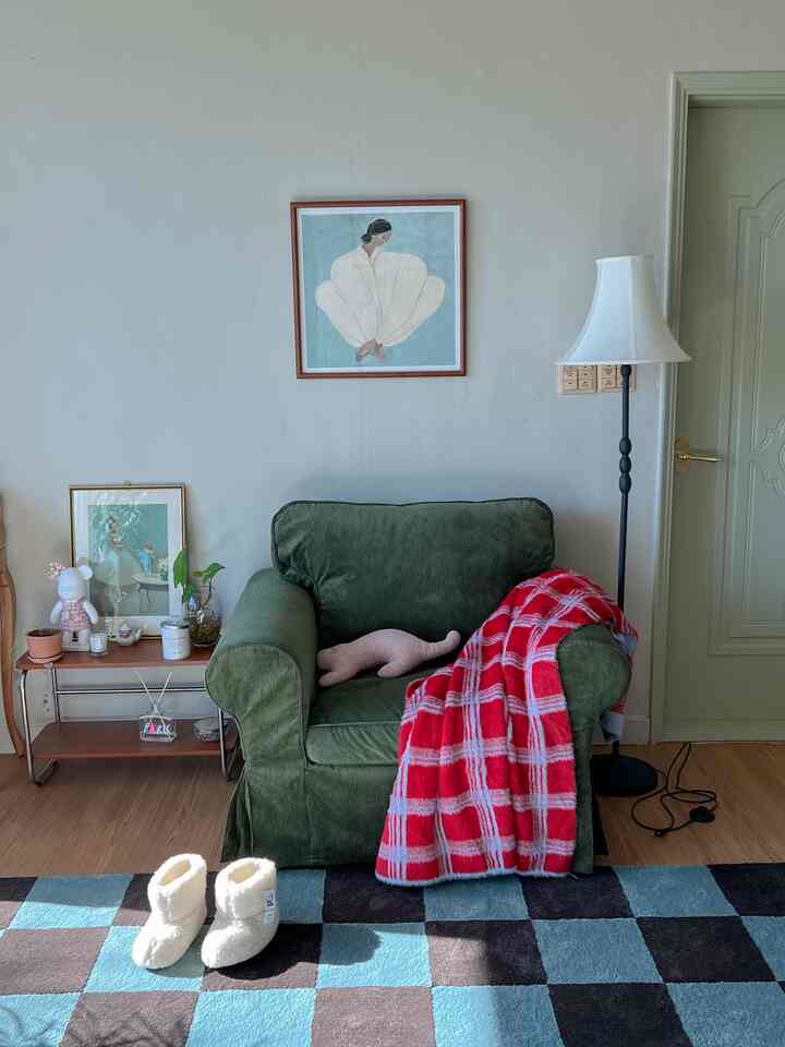 Light gray walls in a vintage living room featuring a green armchair and red checked throw blanket creating a warm atmosphere
