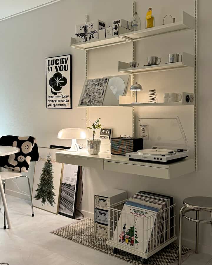 White-toned study room featuring floating system shelves, a turntable, and LP storage basket in Mid-Century Modern style