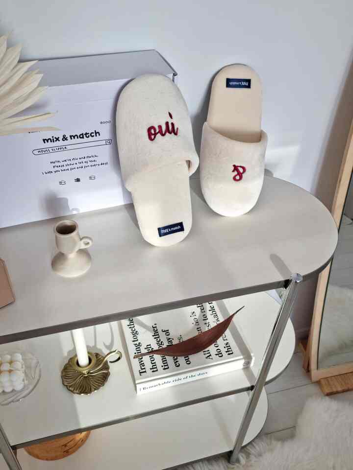 Cream-colored noise-reducing indoor slippers placed on a white-toned shelf with interior accessories, showcasing a clean home styling space