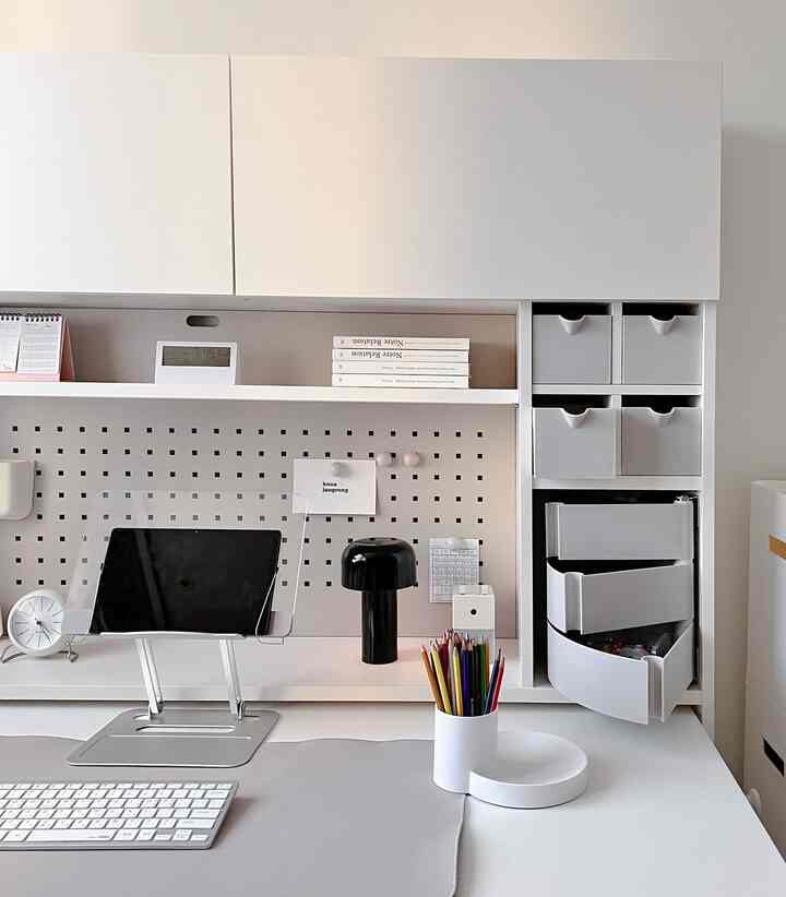 White and gray toned home office space featuring a clean desk with storage drawers and a minimalist organized setup