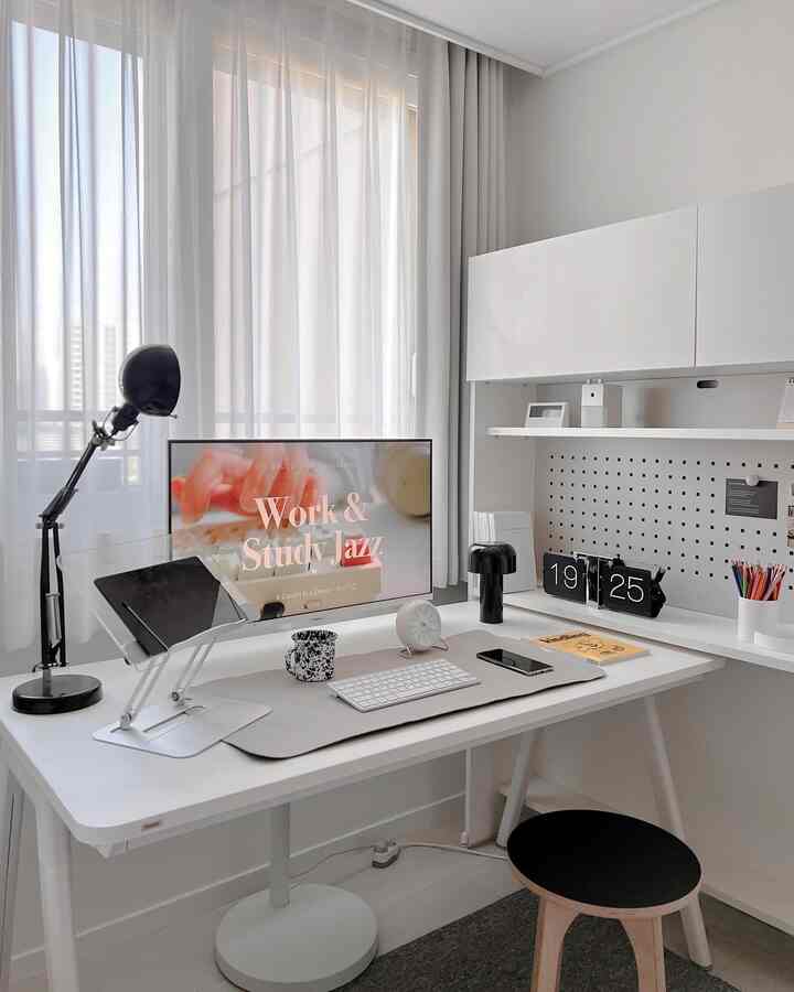White-toned home office space featuring a monitor and desk lamp in a clean, organized work setup
