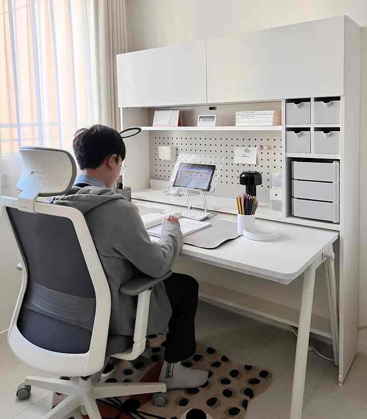 White and gray toned home office featuring a large desk and ergonomic office chair in a neat study space