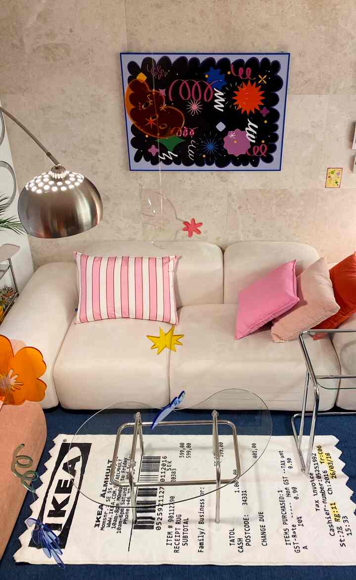 白とピンクのトーンのリビング、ミッドセンチュリーモダンスタイルの大型ソファとクッション、スチール製フロアランプとガラステーブルが配置された雰囲気のあるインテリア