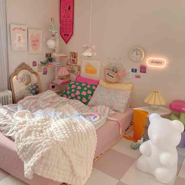 ピンクと白のトーンが調和した寝室、様々な柄の枕と厚手のブランケットが温かみのある雰囲気を演出するインテリア