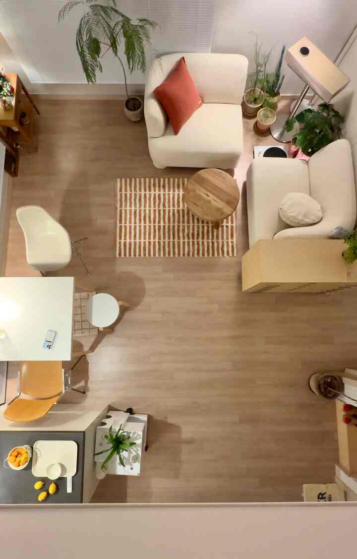 Mid-century modern living room with warm wood flooring and cream sofas, cozy loft space featuring small plants and a floor lamp