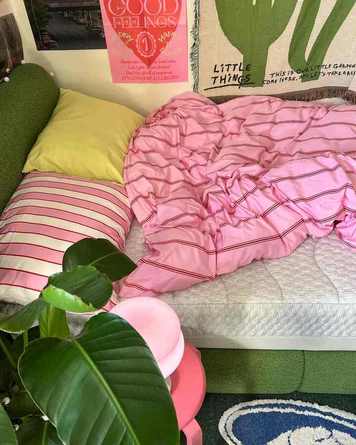 Pink and green toned bedroom featuring bed, pillows, and throw with a cozy natural atmosphere