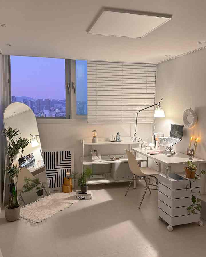 明るいホワイトトーンの書斎空間、大きな窓とブラインド、デスクと棚、植物とランプで飾られた落ち着いた雰囲気のあるインテリア
