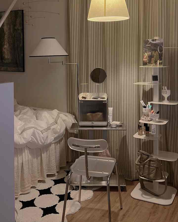 White and natural toned bedroom featuring a simple stool, round mirror, and floor lamp creating a cozy atmosphere