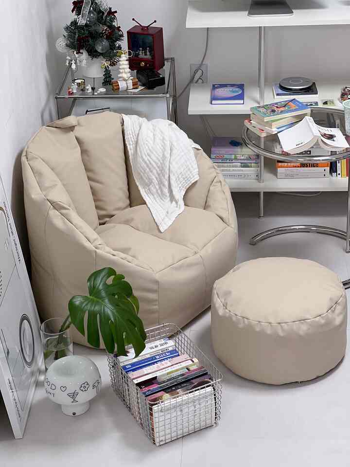 Beige-toned bean bag and stool in a small reading and relaxation space featuring a white throw and organized shelving with a cozy atmosphere