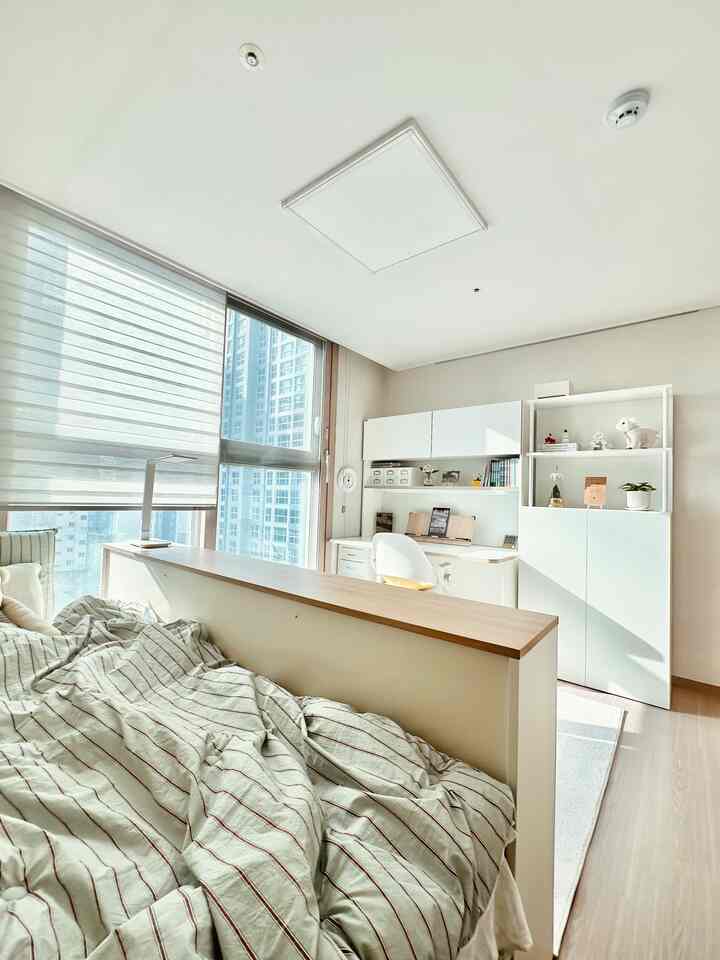 白とナチュラルウッドの調和が取れた子供部屋、ベッドと机が間仕切りで分けられた雰囲気のあるインテリア