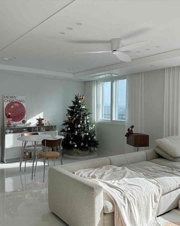 White and natural toned living room featuring a Christmas tree and cozy sofa in a bright space
