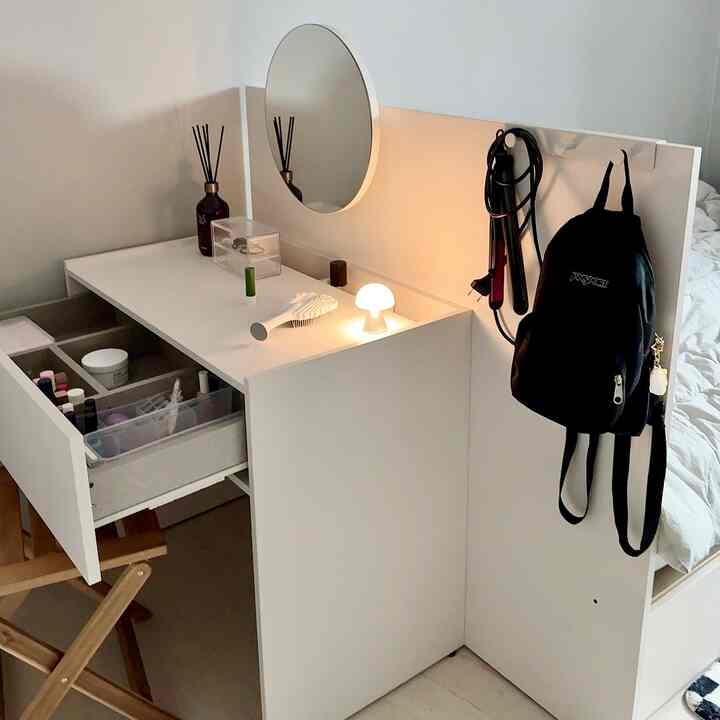 White and natural-toned bedroom featuring a storage vanity with open drawers and a bed frame, creating a tidy space