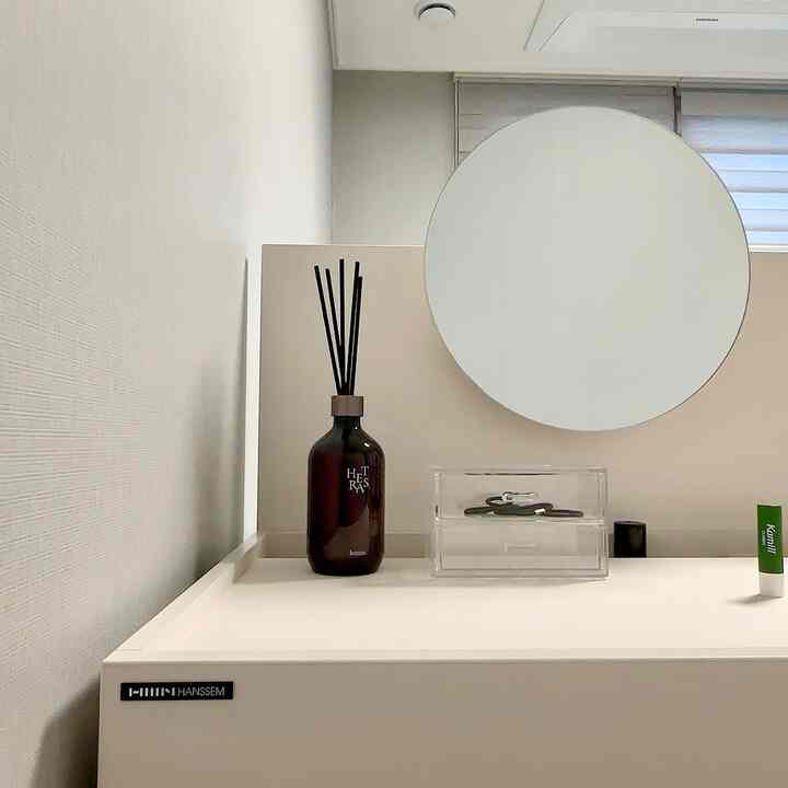White-toned bedroom vanity with minimal diffuser and transparent storage case, creating a clean space