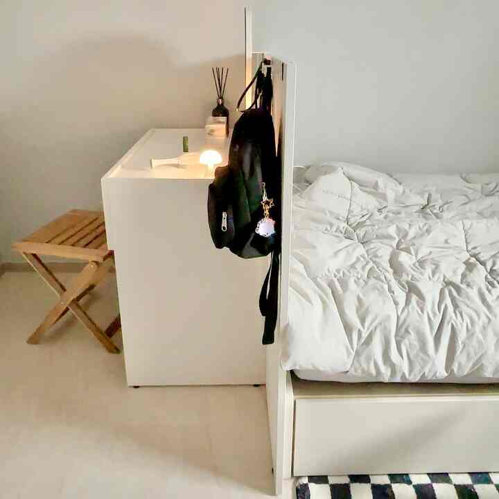 A compact bedroom in white and natural tones featuring a storage bed and modular vanity with minimal design