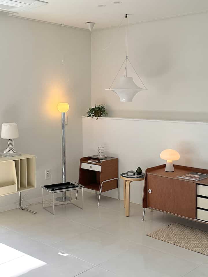 Bright ivory and natural wood tone living room featuring various lamps and nightstands in a clean layout