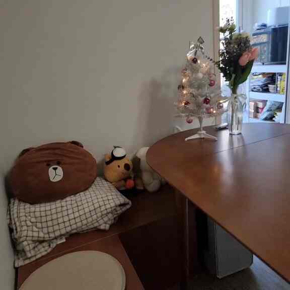 ブラウンの木目調が印象的なワンルームのリビング、コーナーストレージの椅子と大きなダイニングテーブルが配置された雰囲気のある空間