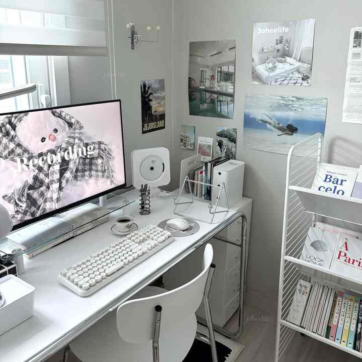White and gray toned home office featuring desk, monitor, and bookshelf arranged neatly for a cozy workspace
