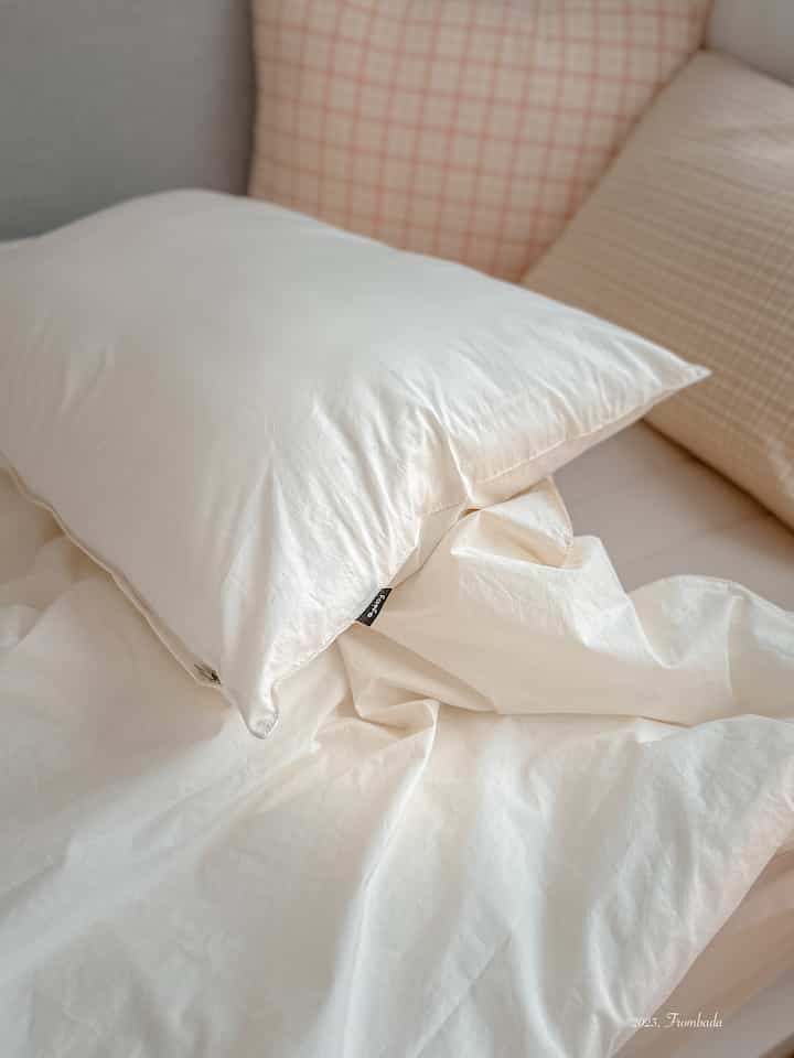 Natural-colored kids' bedroom featuring soft white pillows and check-patterned cushions on cozy bedding