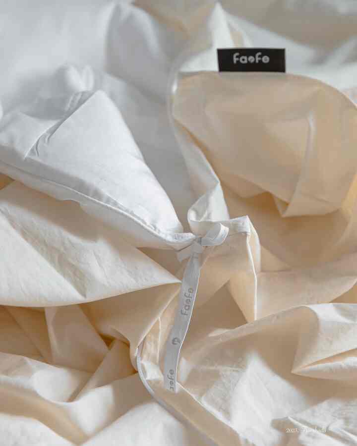 White and ivory toned duvet cover connected with duvet filling, creating a cozy bedroom bedding scene