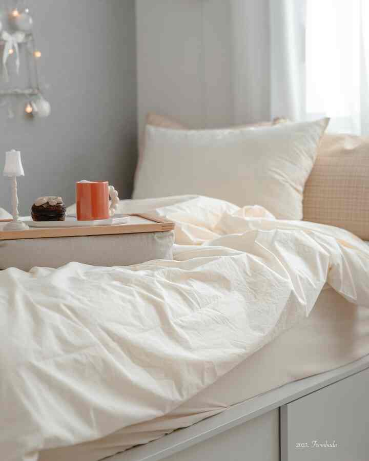 柔らかなホワイトとクリームの子供部屋の寝室、清潔な寝具と小さなベッドトレイが配置された雰囲気のあるインテリア