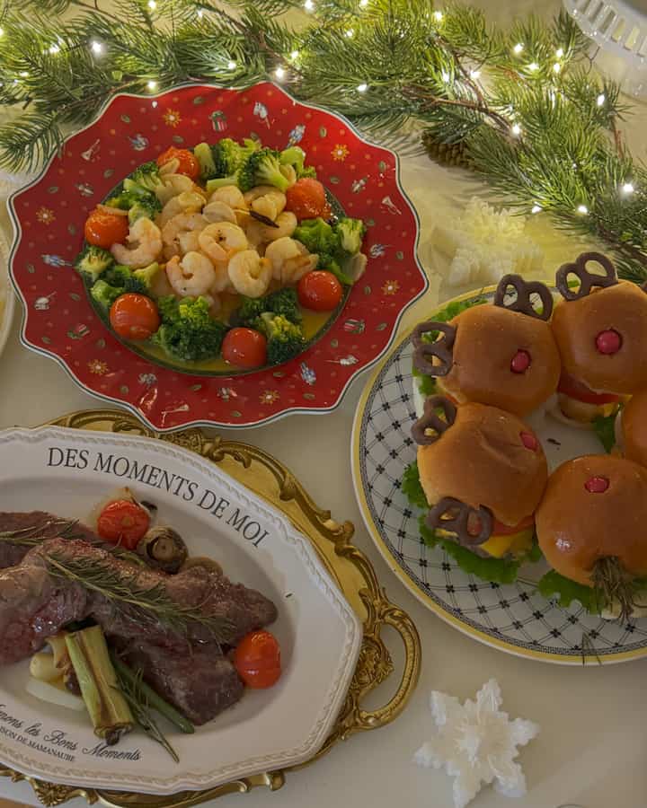 クリスマス風のホームパーティーテーブル、エビとブロッコリーがのった赤い皿とミニバーガーが配置された雰囲気のある空間