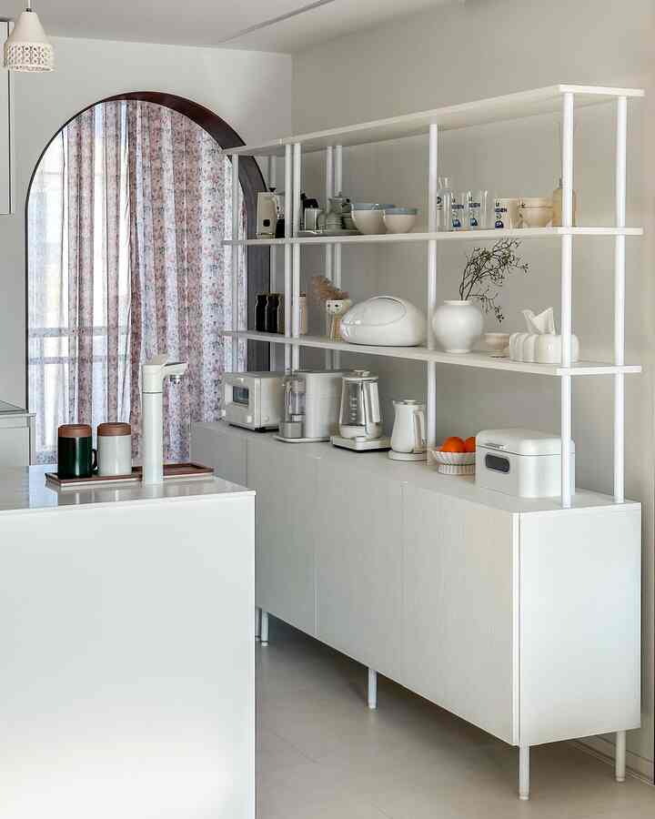 ホワイトトーンのキッチン、シンプルで整理された空間に配置されたシステム棚と収納キャビネット