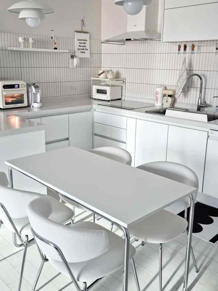 White-tone kitchen space featuring a white dining table and chairs with a clean, modern interior