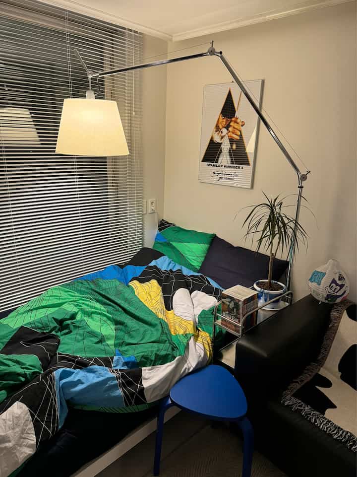 Bedroom with green and blue tones featuring a bed and standing lamp in a cozy setting