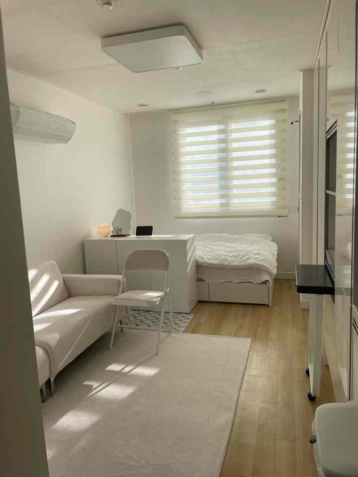 白とベージュのトーンでまとめられた6坪のワンルームオフィステル、ソファとベッド、収納が配置されたシンプルモダンな空間