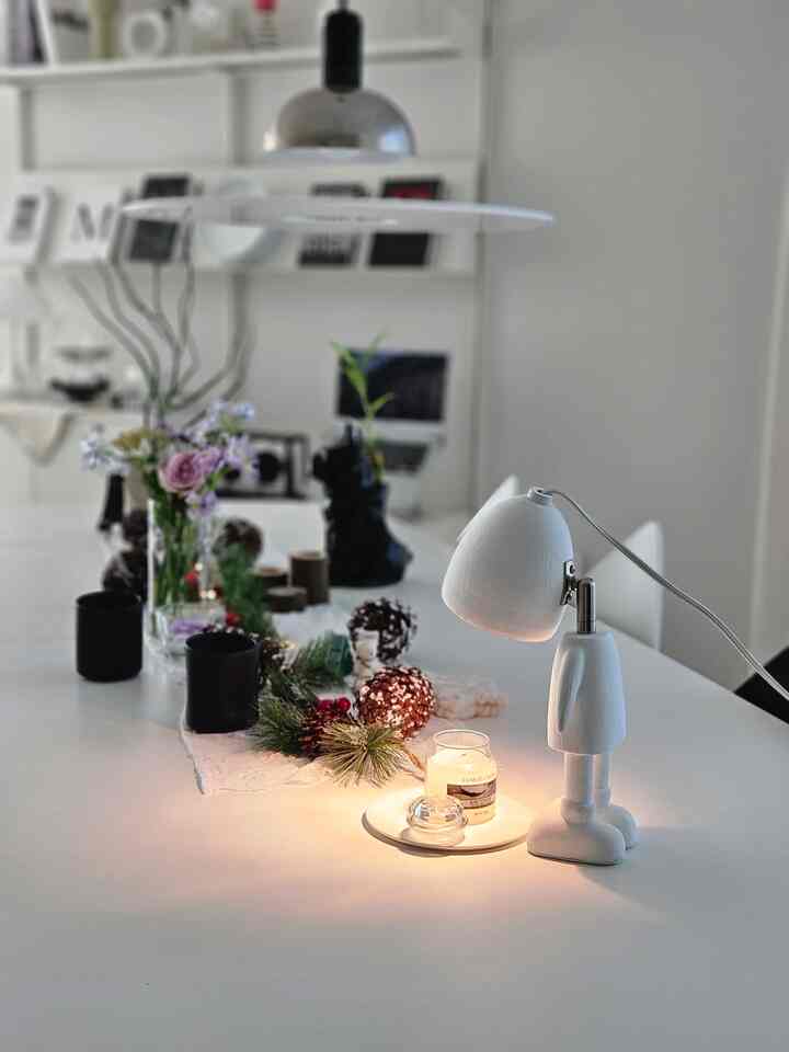 Modern white-toned dining room featuring Christmas garland, candle, and table runner on a sleek table setup