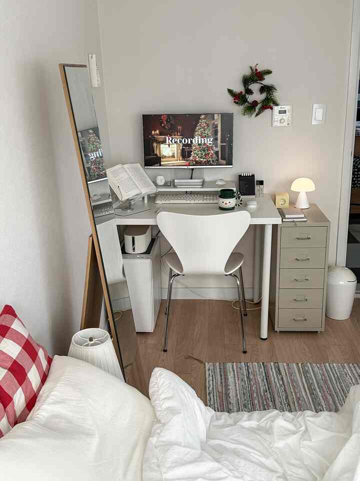 Small bedroom home office in white and beige tones featuring desk with computer and cozy bedding, modern interior
