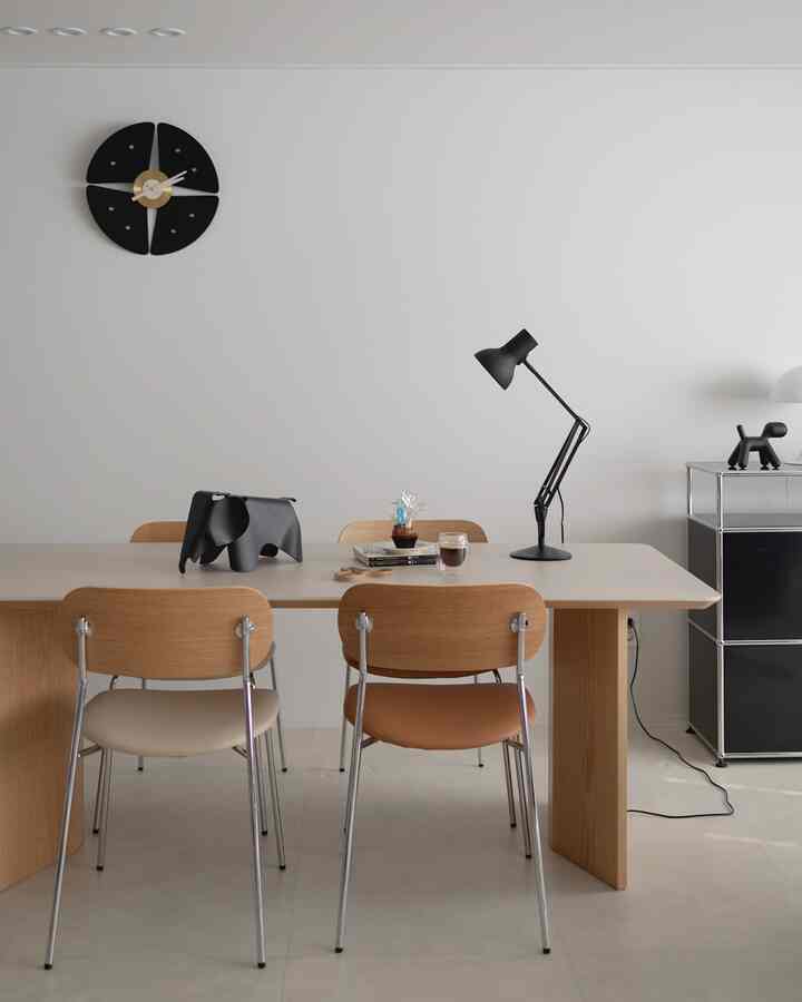 ナチュラルな色調のダイニングルーム、セラミックテーブルとモダンな家具、黒のアクセント小物が配置された印象的な空間