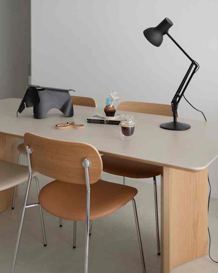 Natural color toned dining room with simple dining table and chairs, featuring table lamp and coffee cup in a sleek setting