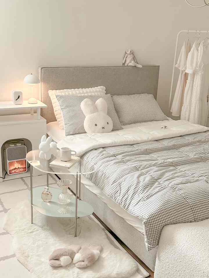 Natural and white toned bedroom featuring beige bed with checked bedding, clothes rack and warm lighting creating cozy atmosphere