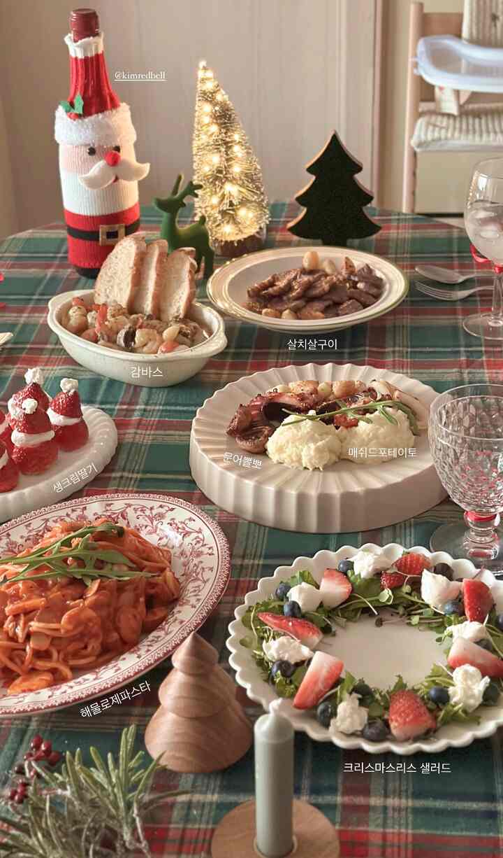 Warm white and green toned home party dining table featuring Christmas decorations and assorted home-cooked dishes in a cozy setting
