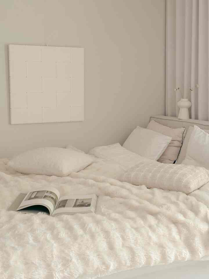 アイボリー調の寝室、柔らかな寝具とシンプルな壁の装飾が落ち着いた雰囲気を醸し出す空間