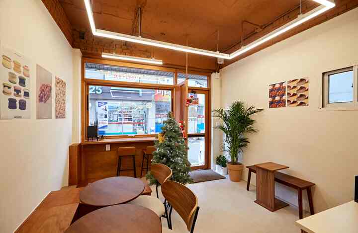 木目調のナチュラルなカフェ風インテリア、窓際のバースツールとテーブル、温かみのある照明が印象的な空間